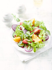 Salad with red and yellow Tomatoes and Pomegranate Seeds on bright wooden Background. Close up.