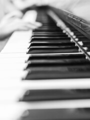 Piano keys closeup. Musical instrument in black and white photo. The hands of a musician playing the piano are out of focus .