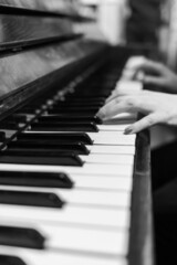 Obraz premium Piano keys closeup. Musical instrument in black and white photo. The hands of a musician playing the piano are out of focus .