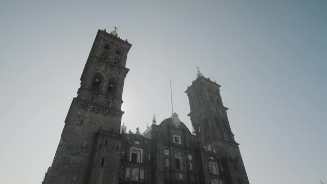 Bottom up shot of beautiful historic ROman Catholic Puebla Cathedral against blue sky and sun in Mexico
