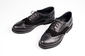 Black imitation leather shoes laced with wide laces. Close-up shot.