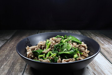 Traditional fried pork sliced with fresh Chinese kale serving on the plate. Famous comfortable food menu in Asia restaurant. 