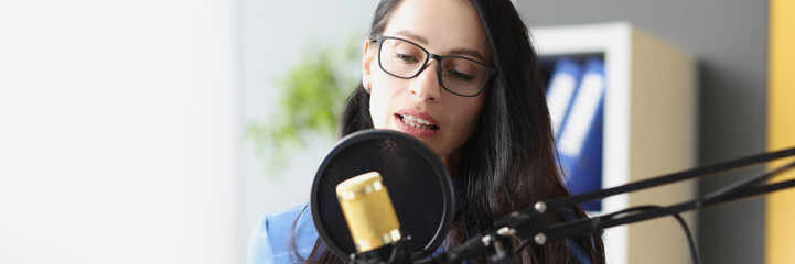 Young beautiful woman speaks into microphone at workplace