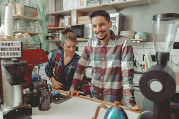Portrait of happy couple working as barista together in modern cafe