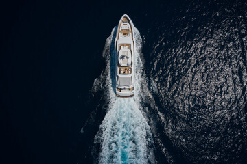 Big white super boat moves on the water aerial view. Big yacht for millionaires in the sea drone...