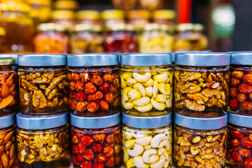 bee honey with nuts in glass cans on counter of market