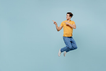 Full body happy young man 20s wear yellow t-shirt jup high point index finger aside on workspace...