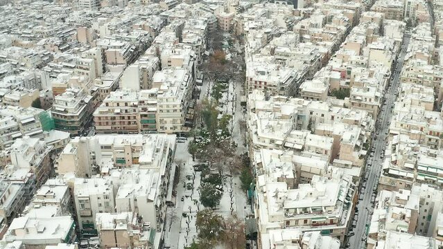 Aerial tilt up view Fokionos Negri street white scenery from snowfall reveal Athens cityscape. Greece