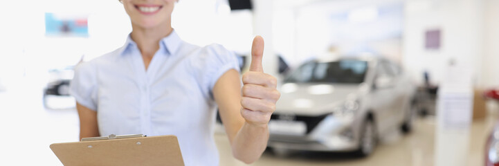 Car sales manager holds thumbs up in car dealership