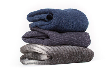 Knitted winter clothes neatly folded in a pile on a white background. The surface of men's woolen things, textiles. Closeup knitted texture. Background with copy space. Casual wear.