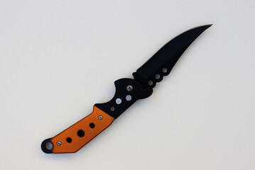 Isolated designer black knife with orange handle. Isolated knife with textured white background. knife on paper