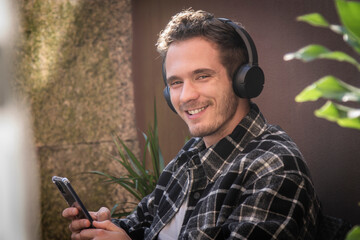smiling boy using mobile phone with earphones