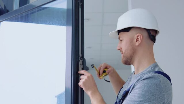 Window installer measures the dimensions of the window frame with a meter tape