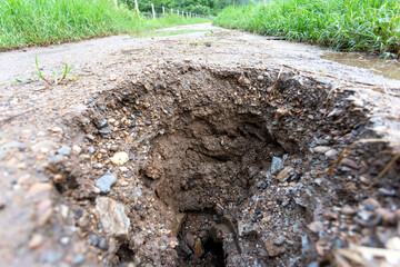 big hole on the ground country road due to broken pipes under the road See the dangers of traveling on broken paths. Roads are often damaged during the rainy season.