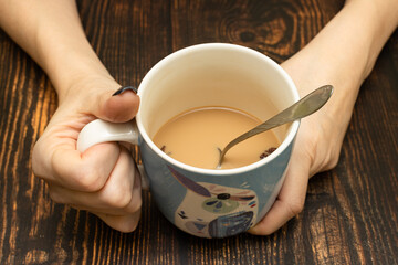 female hands hold a large mug of cappuccino