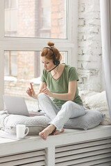 Beautiful young woman working remotely or studying at home at her laptop in the living room