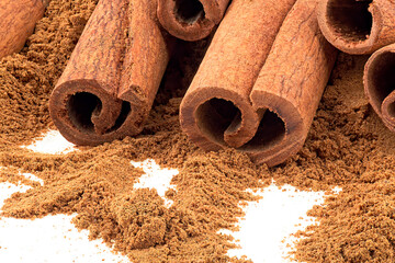 Cinnamon sticks with cinnamon powder on a white background, close up.