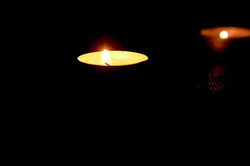 Round candles.Two lighted candles glow on a dark background.Low-light atmosphere.