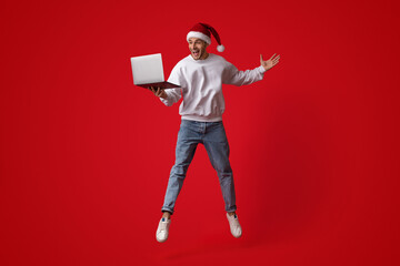 Online Win. Happy Excited Man In Santa Hat Jumping With Laptop