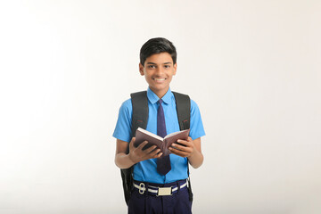 Indian school boy in uniform and reading diary on white background.