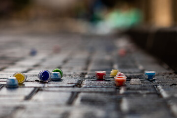 Plastic, single use water bottle tops litter a cobblestone street following a road race. 