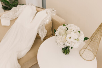 A luxurious wedding dress and a white bridal bouquet of roses, chrysanthemums