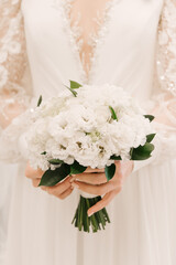 Beautiful white bridal bouquet of roses, chrysanthemums, eustoma in the hands of the bride