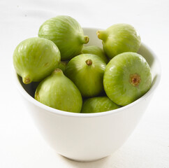 Higos verdes en bol blanco de cerca. Green figs in white bowl close up.