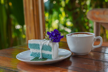 front view three flowers on Coconut Cake on green banana leaf on white ceramic plate and coffee in white ceramic mug, on wooden floor background, food, dessert, copy space