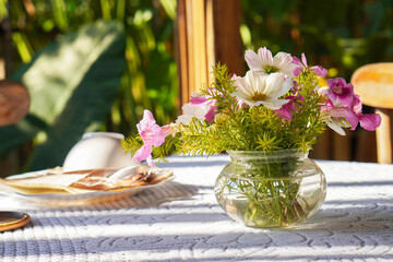 front view pink and white flowers and green leaf in glass vase on white fabric on table, blur nature background, nature, decor, object, copy space
