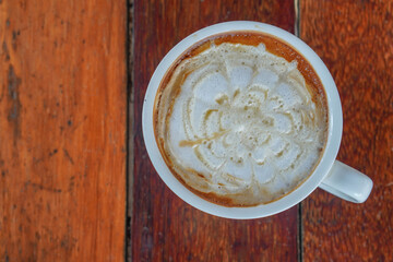 top view, hot caramel macchiato coffee in white ceramic cup on a wooden table.