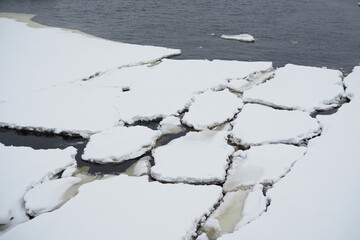 Ice with snow melts on the water. Winter view of the river