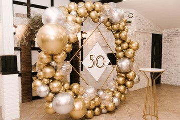 The round photo zone is decorated with gold and silver balls for the 50th birthday, the work of an...