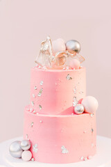A large pink cake with a pink photo zone of silver balloons on the background. Party decorated with balloons