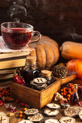 wooden runes are lying on the table. Next to a box of bottles and a mug of tea