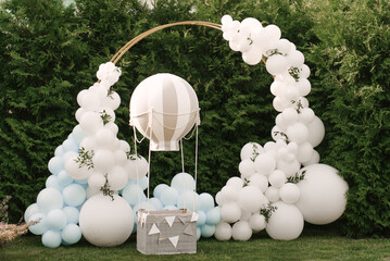 Decorations for holiday party. A lot of balloons blue and white colors. Round photo zone with balls next to a ball with a basket for a child