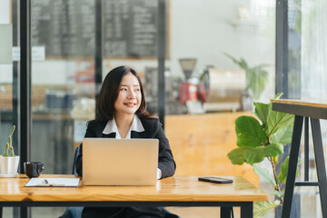 Portrait of a happy casual businesswoman in suit sitting at her workplace in office