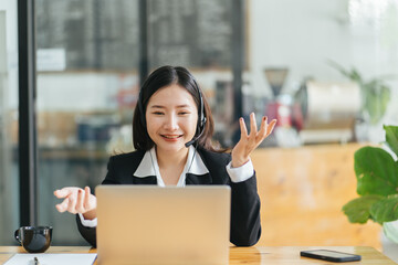 Side view head shot smiling asian lady freelancer wearing headset, communicating with client via video computer call. Millennial pleasant professional female tutor giving online language class.