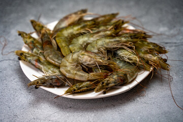 Raw shrimps lie on a white plate.