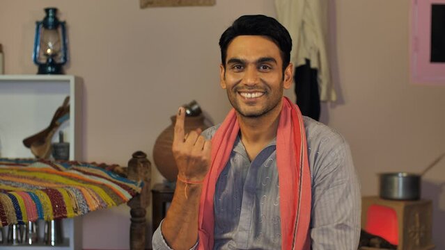 A happy farmer showing his ink-marked finger while sitting at home - elections  State elections  National elections  Voter. A modern and educated farmer showing his ink-marked index finger after ca...