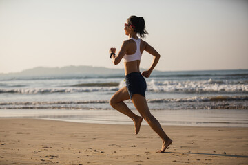 Fitness woman running on beach