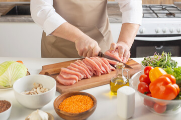 man cuts meat on  table in  kitchen