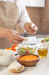 Obraz na płótnie Canvas man adding microgreens to salad in kitchen