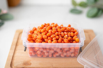 frozen ripe sea buckthorn in a plastic container