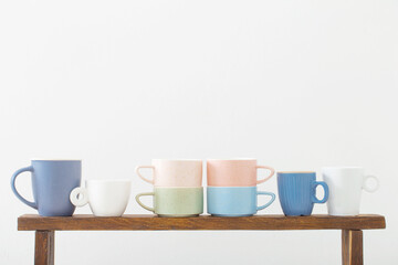 colorful cups on  wooden shelf on  white background