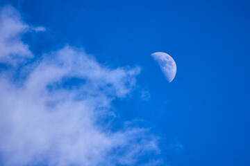 the moon in the blue sky with clouds at dusk