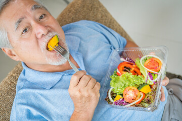 Mature man with pumpkin and healthy food, Portrait Asian Senior man eating a salad in house, Old elderly male health care eat vegetables and useful foods.