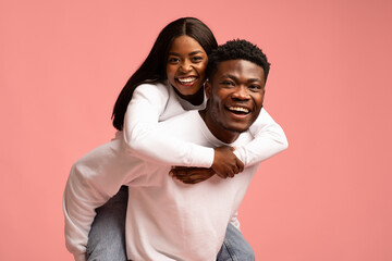 Pretty black woman piggyback her boyfriend, smiling at camera