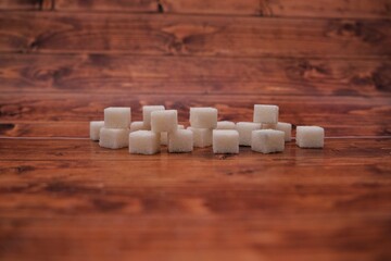 Fototapeta na wymiar Cubes of sugar. Sugar cubes on wooden background.
