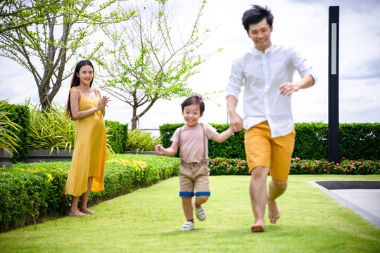 happy asian family playing on the lawn at home.